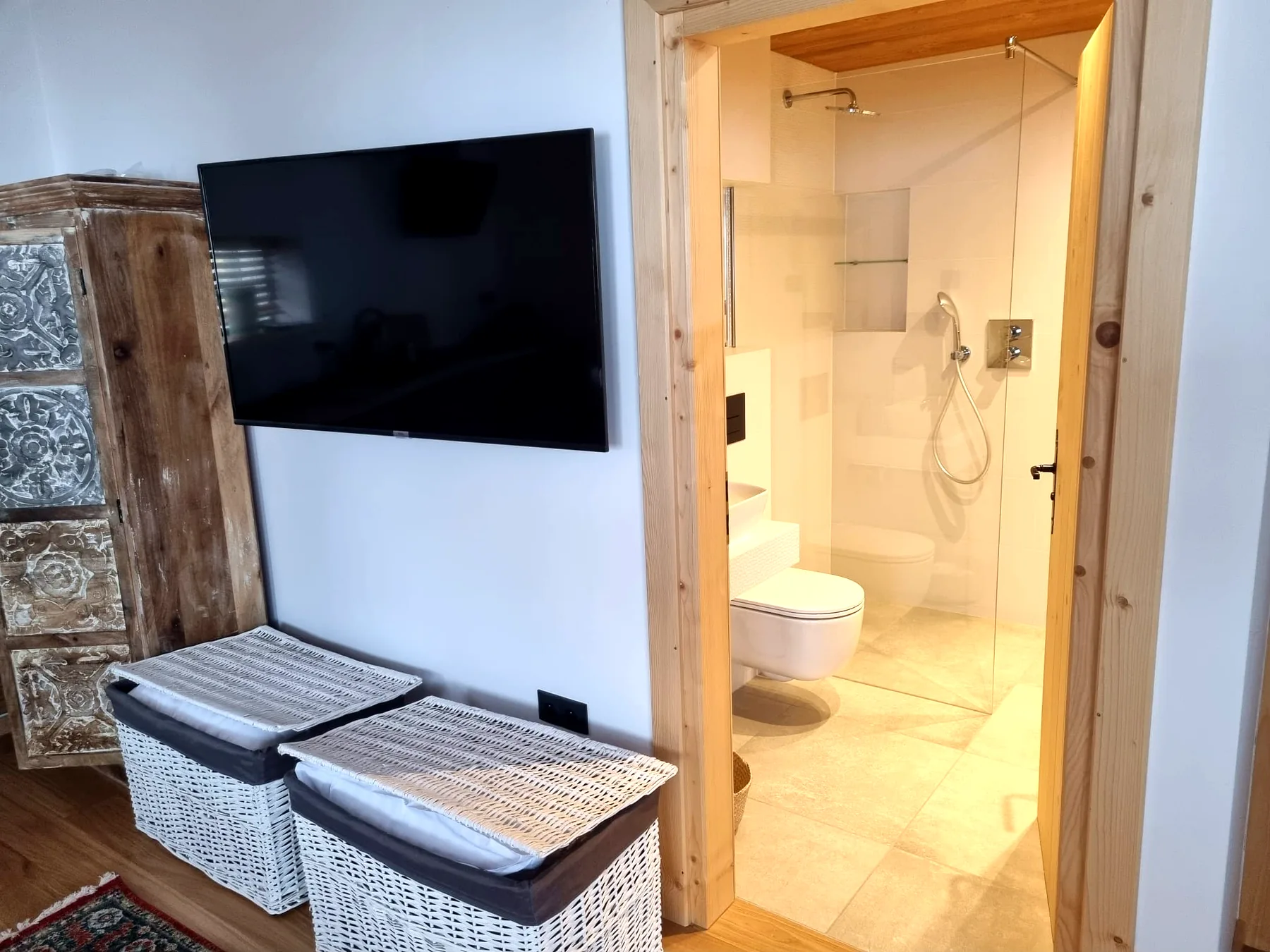 Wejście do łazienki Apartamentu 4 obok telewizora i drewnianej szafy